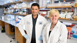 a man and a woman in lab coats and gloves stand together in a lab